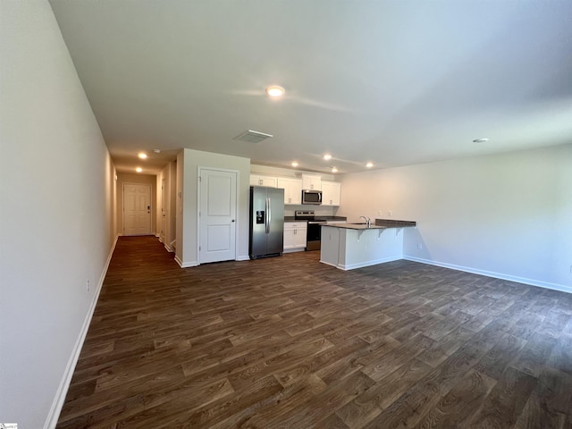 kitchen with appliances with stainless steel finishes, white cabinetry, sink, kitchen peninsula, and dark wood-type flooring