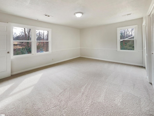 carpeted spare room featuring plenty of natural light and a textured ceiling