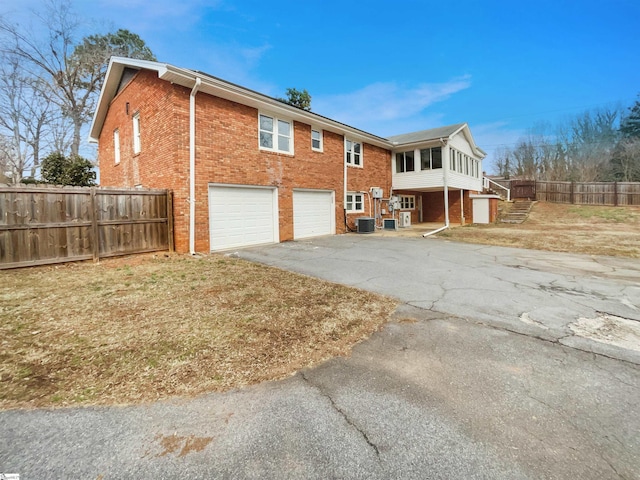 back of property with a garage and central AC