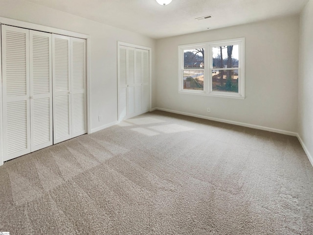 unfurnished bedroom with multiple closets and carpet floors