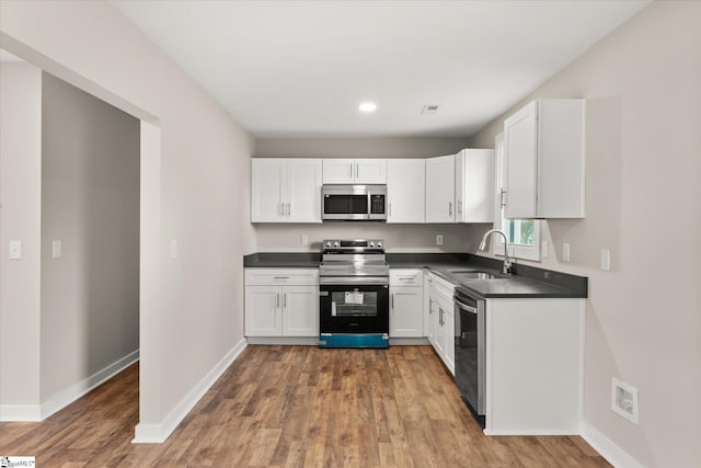 kitchen with appliances with stainless steel finishes, dark hardwood / wood-style flooring, sink, and white cabinets