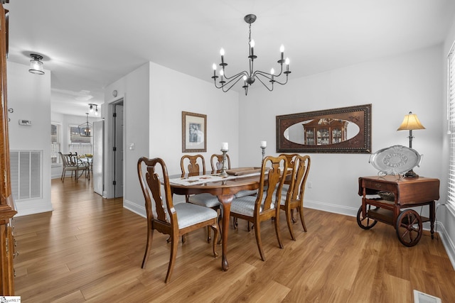 dining space with a notable chandelier and light wood-type flooring