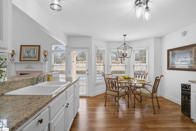 kitchen with sink, decorative light fixtures, dark hardwood / wood-style flooring, light stone countertops, and white cabinets