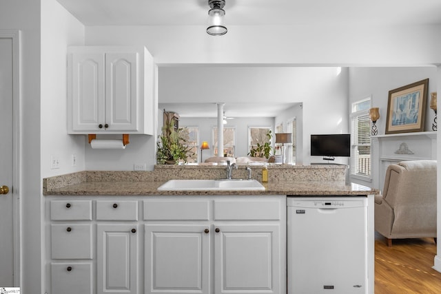 kitchen featuring sink, white cabinetry, light hardwood / wood-style flooring, white dishwasher, and light stone countertops