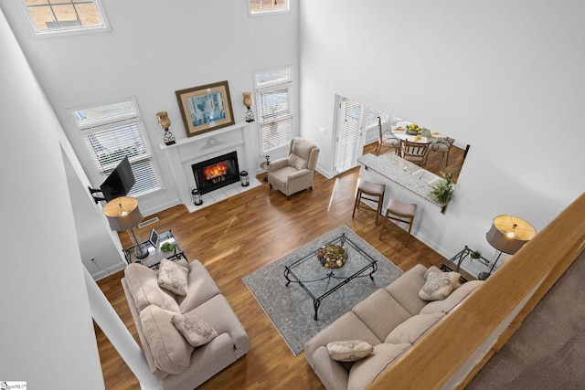 living room with hardwood / wood-style flooring, plenty of natural light, and a towering ceiling