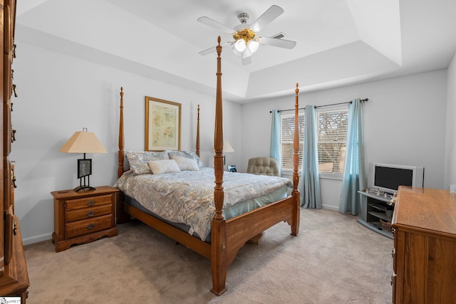 bedroom with ceiling fan, a tray ceiling, and light colored carpet