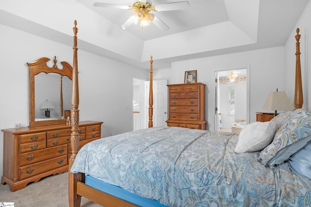 carpeted bedroom featuring ceiling fan, ensuite bath, and a tray ceiling