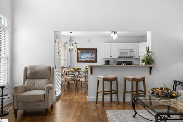 kitchen with white cabinetry, hanging light fixtures, light stone countertops, and a healthy amount of sunlight