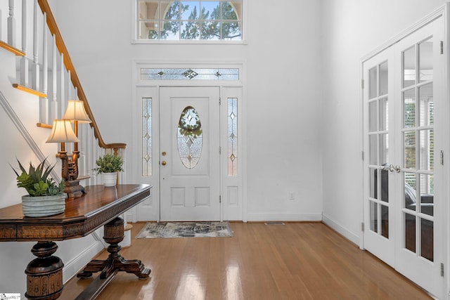 foyer entrance featuring a high ceiling, french doors, and light hardwood / wood-style flooring