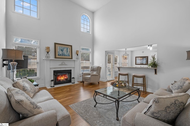 living room featuring a high ceiling, a healthy amount of sunlight, and light hardwood / wood-style flooring