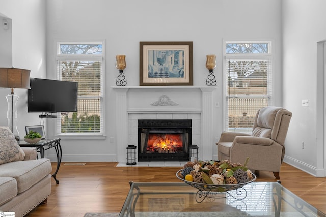 living room with hardwood / wood-style flooring and a tiled fireplace