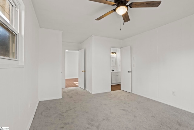 unfurnished bedroom featuring sink, light carpet, ceiling fan, and ensuite bath