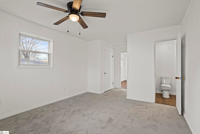 unfurnished bedroom with ensuite bathroom, light carpet, and ceiling fan