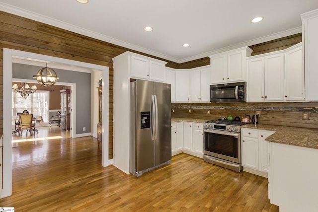 kitchen featuring light stone counters, ornamental molding, appliances with stainless steel finishes, and white cabinets