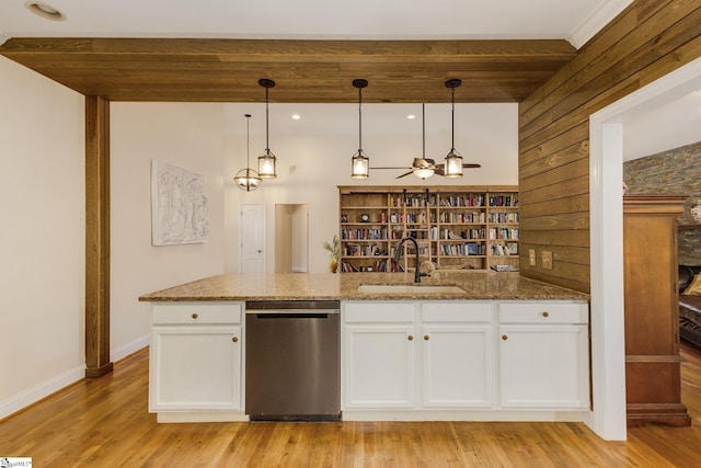 kitchen featuring white cabinetry, sink, wooden walls, and dishwasher