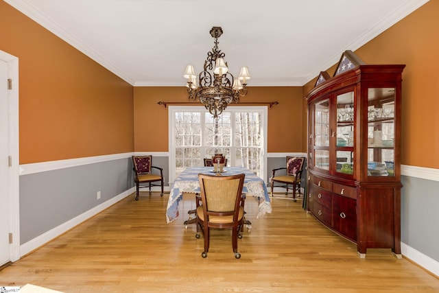 dining space with crown molding, light wood-type flooring, and a chandelier