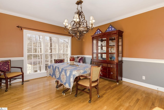 dining room with crown molding, light hardwood / wood-style flooring, and a notable chandelier