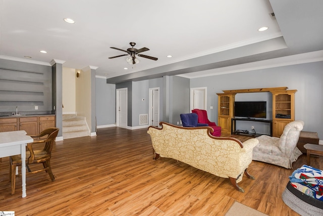 living room with crown molding, light hardwood / wood-style flooring, built in shelves, and ceiling fan