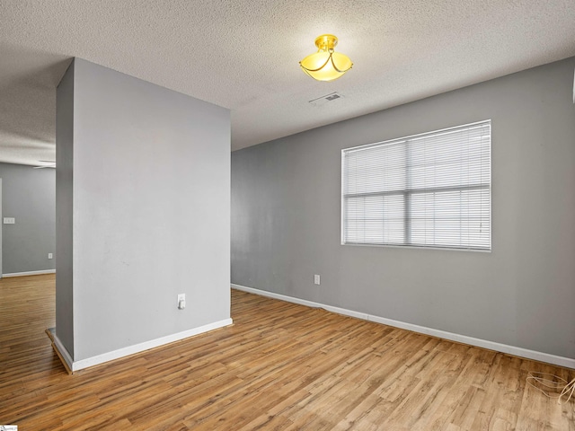 unfurnished room with a textured ceiling and light wood-type flooring