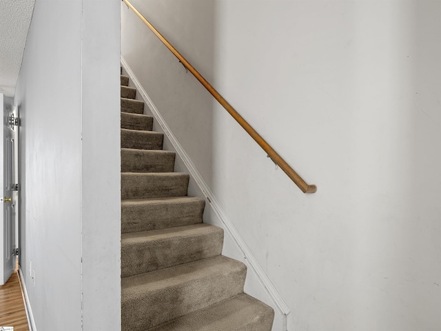 stairway with hardwood / wood-style floors and a textured ceiling