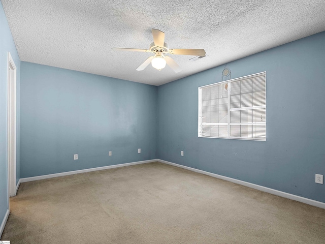 empty room featuring ceiling fan, light carpet, and a textured ceiling