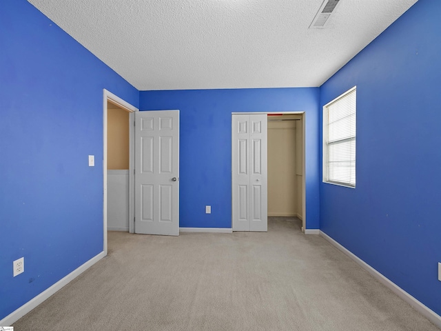 unfurnished bedroom with light carpet, a closet, and a textured ceiling