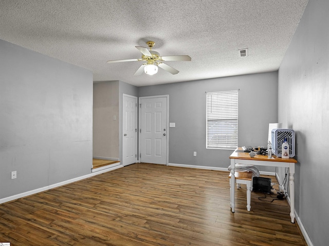 unfurnished office featuring a textured ceiling, dark wood-type flooring, and ceiling fan