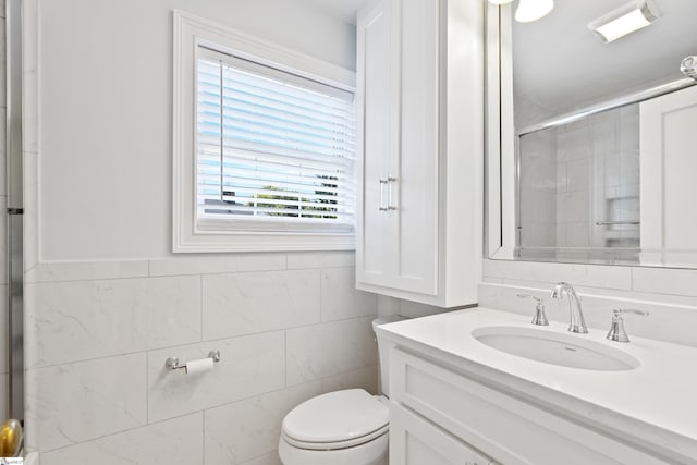 bathroom featuring vanity, toilet, an enclosed shower, and tile walls