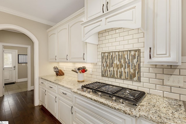 kitchen with stainless steel gas stovetop, white cabinets, light stone counters, and decorative backsplash