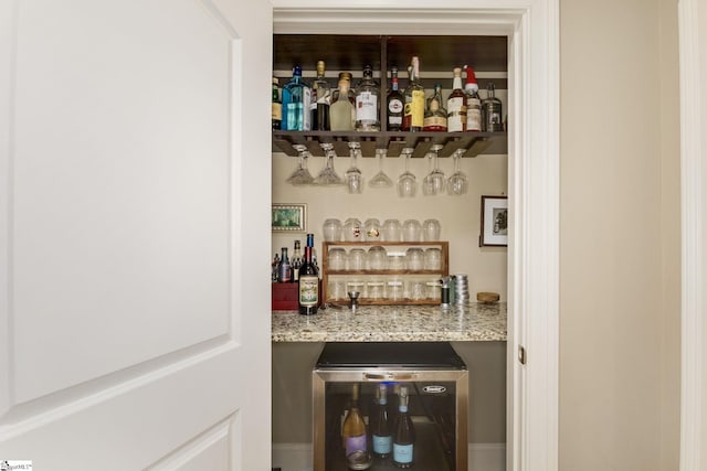 bar with light stone counters, fridge, and beverage cooler