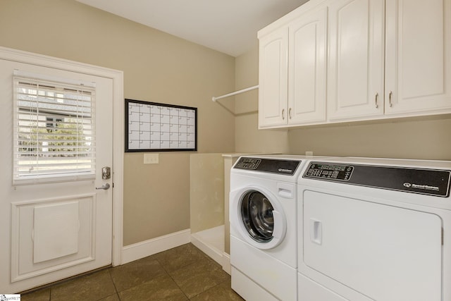 washroom with dark tile patterned flooring, cabinets, and washing machine and clothes dryer