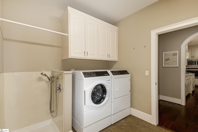 laundry area featuring washing machine and dryer and dark tile patterned floors