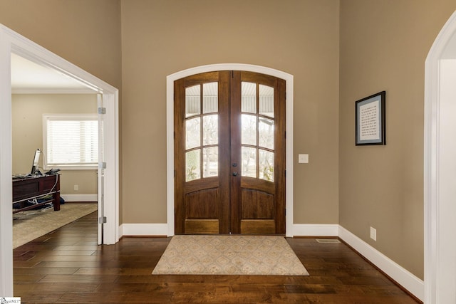 foyer featuring ornamental molding, dark wood-type flooring, and french doors