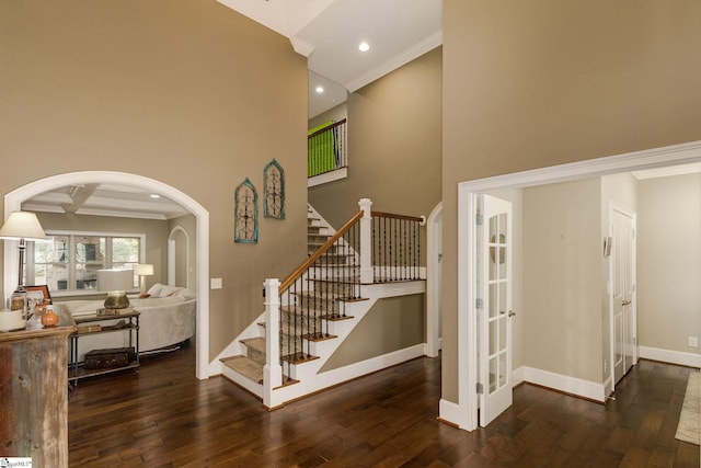 staircase with coffered ceiling, crown molding, hardwood / wood-style flooring, beamed ceiling, and a high ceiling