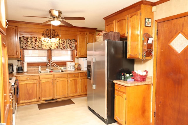 kitchen featuring ceiling fan, sink, stainless steel fridge with ice dispenser, and stove