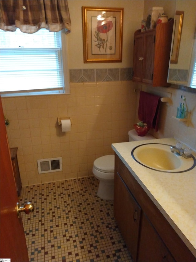 bathroom featuring vanity, toilet, tile patterned flooring, and tile walls