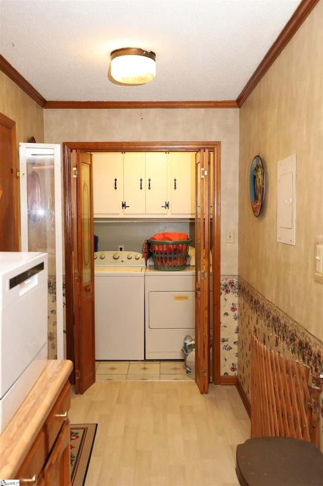 laundry room with crown molding, a textured ceiling, cabinets, and washing machine and clothes dryer