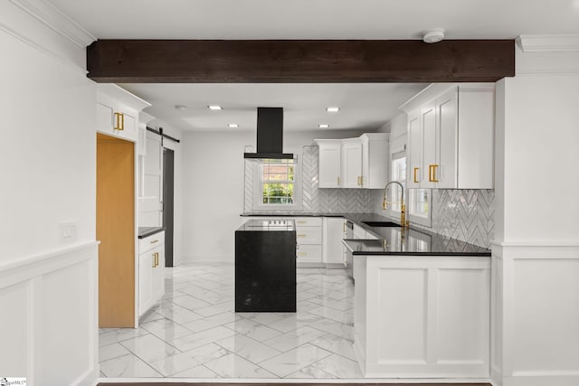 kitchen featuring white cabinetry, sink, decorative backsplash, exhaust hood, and a barn door