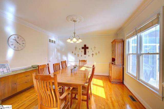 dining area featuring crown molding, a chandelier, and light wood-type flooring