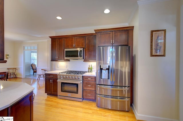 kitchen with stainless steel appliances, ornamental molding, backsplash, and light wood-type flooring