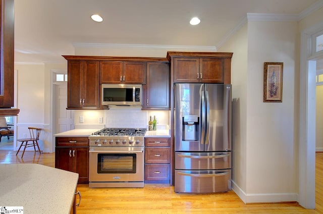 kitchen featuring crown molding, stainless steel appliances, decorative backsplash, and light wood-type flooring