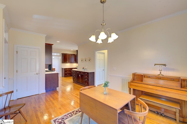 dining space with crown molding, a chandelier, and light hardwood / wood-style floors