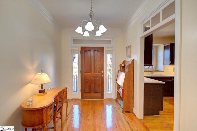 foyer entrance with crown molding, sink, a notable chandelier, and light hardwood / wood-style flooring