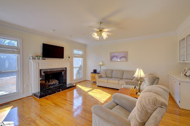 living room with ornamental molding, plenty of natural light, and light hardwood / wood-style floors