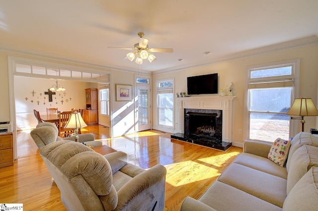 living room with a high end fireplace, ornamental molding, and light hardwood / wood-style floors