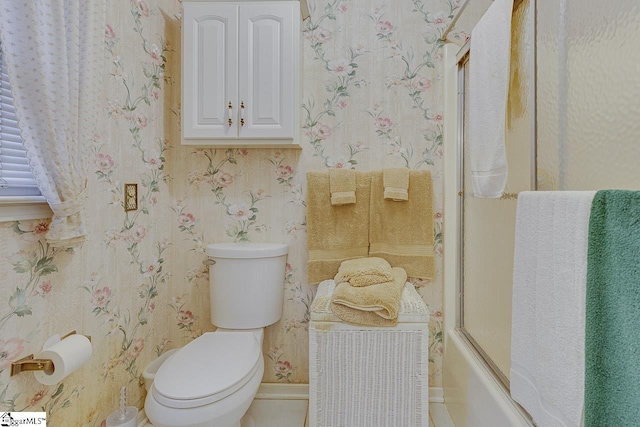 bathroom with bath / shower combo with glass door and toilet