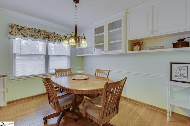 dining room with ornamental molding, a notable chandelier, and light wood-type flooring