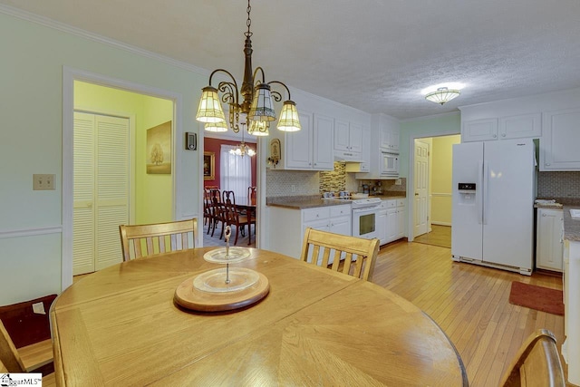 dining room featuring crown molding, a chandelier, light hardwood / wood-style flooring, and a textured ceiling