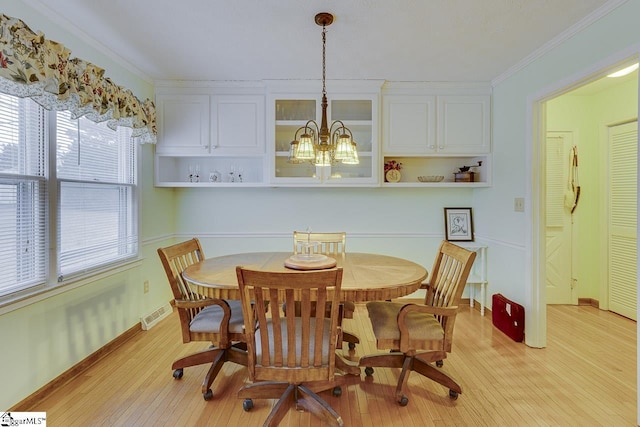 dining area with a notable chandelier, ornamental molding, and light wood-type flooring