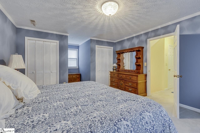 bedroom with ornamental molding, two closets, light colored carpet, and a textured ceiling